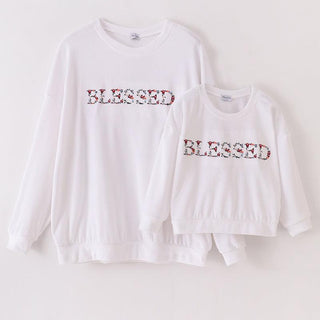 A white velvet sweatshirt with 'blessed' embroidered on the front, displayed in two different sizes, with the smaller size shown from a side view and the larger size shown from the front.