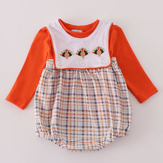 Baby romper with orange long-sleeve top and plaid bottom on a light gray background