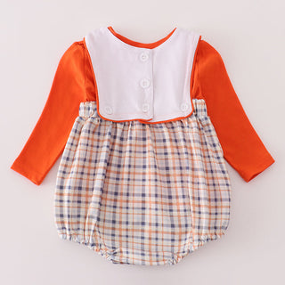 Baby romper with orange long-sleeve top and plaid skirt on a light gray background