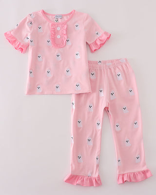 Pink pajama set with ruffled details on a light gray background