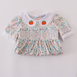 Floral smocked top with pumpkin details on a light gray background