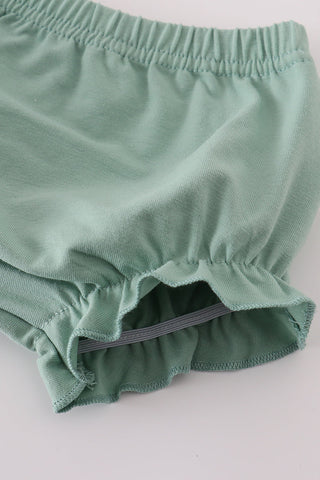 Green baby bloomers on a light gray background