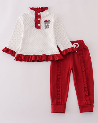 Children's outfit with white top and red pants on a light gray background