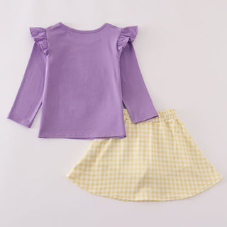 Purple top with ruffled sleeves and a yellow checkered skirt on a light gray background