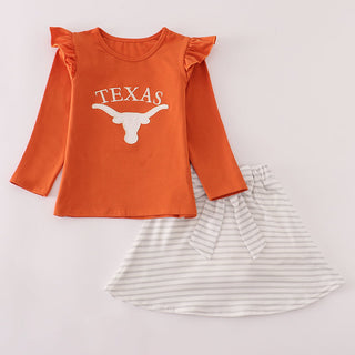 Orange long-sleeve shirt with 'Texas' and a bull logo, paired with a striped skirt on a light gray background.