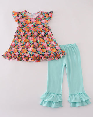 Pumpkin top and turquoise pants with ruffled hem on a light gray background