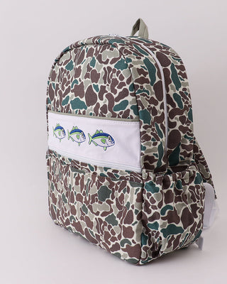 Backpack with camouflage pattern and white patch with fish design on a light gray background