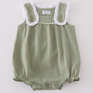 Green baby romper with white lace trim on a light gray background