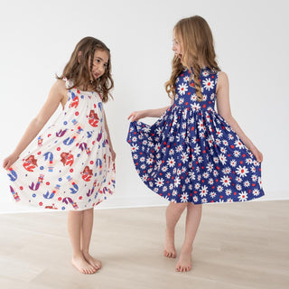 Two girls wearing colorful floral dresses on a plain background