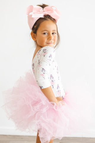 Young girl wearing a ballerina pattern pink tutu leotard on a white background
