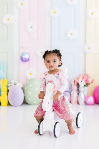 Child sitting on a balance bike with a colorful, pastel-themed background