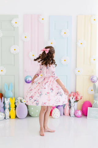 Child in a floral dress standing in front of a colorful background.