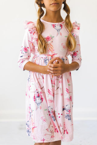 Young girl wearing a floral dress with long sleeves on a white background