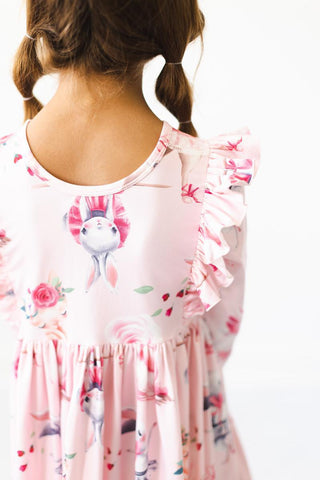 Back view of a child wearing a pink floral dress with ballerinas on a white background
