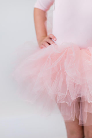 Close up of girl wearing a pink tutu leotard on a white background