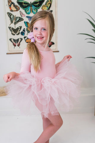 Young girl in a pink tutu dance leotard with a butterfly-themed wall art in the background