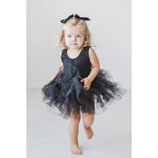 Child wearing a black tutu dress with a bow on a white background