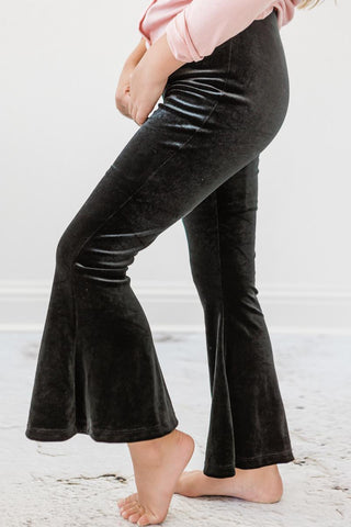 Black velvet flared pants worn by a person on a light gray background