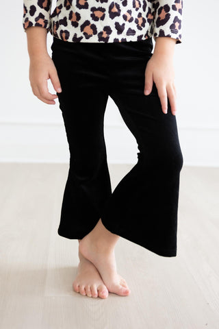 Person wearing a leopard print top and black pants on a light background