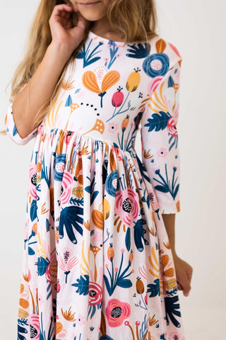 Child wearing a colorful floral dress against a white background