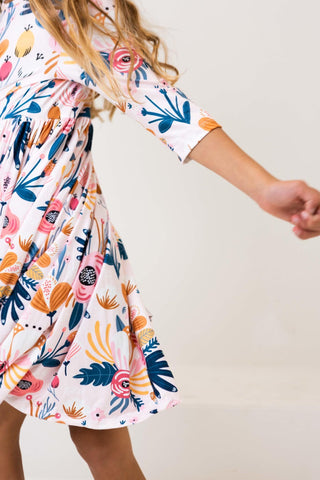 Girl wearing a colorful floral dress against a plain background