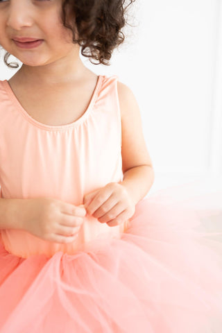 Child wearing a pink leotard with a white background