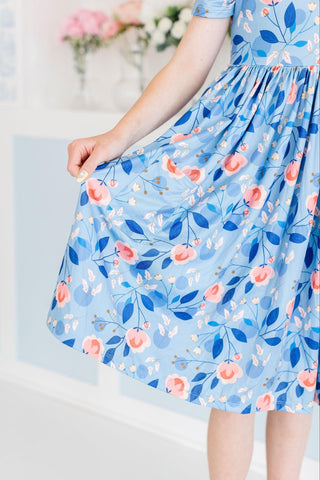 Person wearing a blue floral dress with a light background