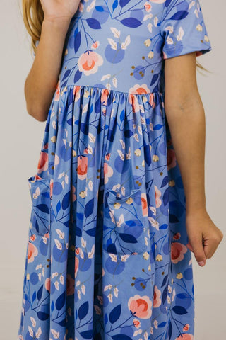 Child wearing a blue floral dress on a plain background