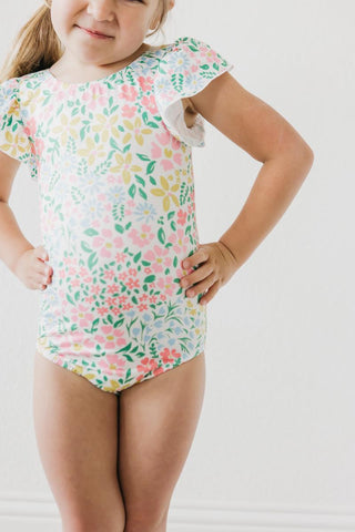 Child wearing a floral leotard on a plain background