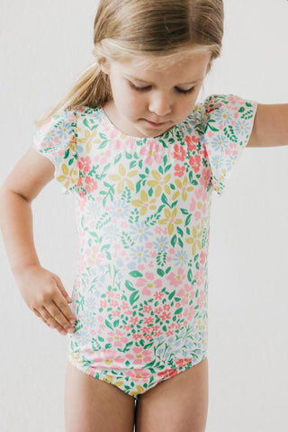Young girl wearing a floral leotard on a plain background