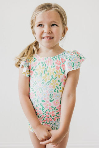 Young girl wearing a floral leotard against a plain background