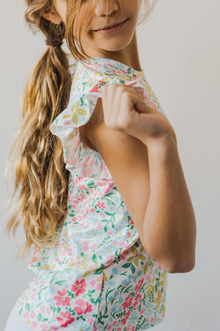 Young girl wearing a floral top with a plain background
