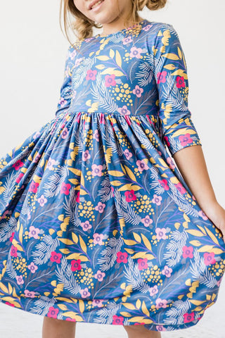 Child wearing a blue floral dress with a plain background
