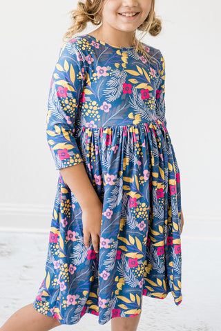 Child wearing a blue floral dress against a white background