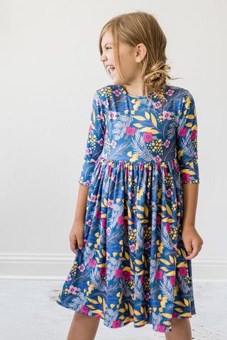 Young girl wearing a blue floral dress against a white background