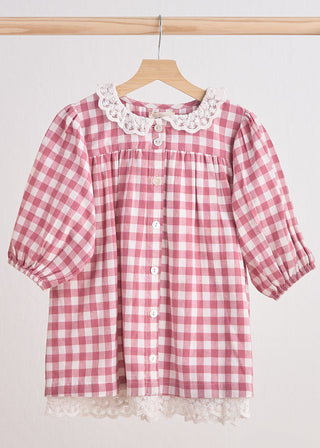 A pink gingham flannel lace dress with a round neckline and short sleeves, hanging on a wooden hanger.