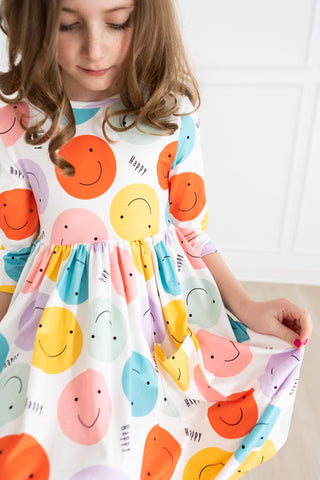 Child wearing a dress with colorful smiley face pattern