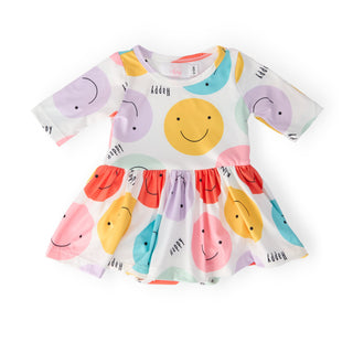 Colorful baby’s dress with smiley face design on a white background