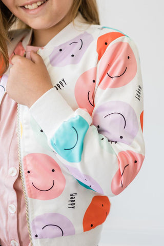 Child wearing a jacket with colorful smiley face pattern