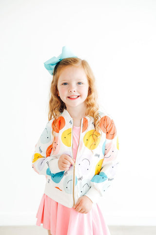 Young girl wearing a colorful jacket with cartoon designs on a white background