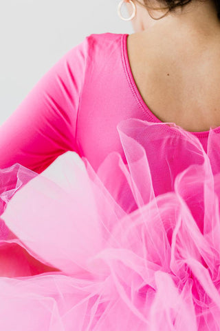 Close-up of a person wearing a bright pink long-sleeve leotard with a tulle skirt.