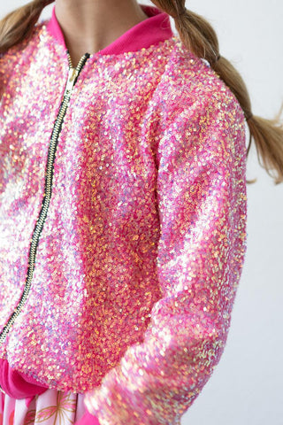 Close-up of a pink sequin jacket worn by a person with a plain background