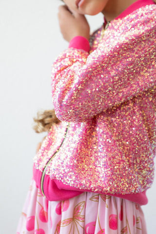 Person wearing a pink sequin jacket with a white background