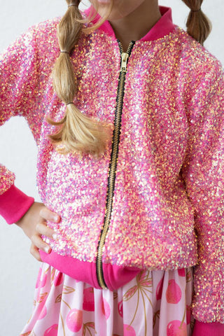 Child wearing a pink sequin jacket with a white background