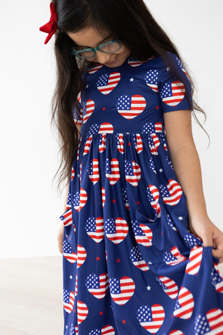 Girl wearing a blue dress with American flag pattern on a white background