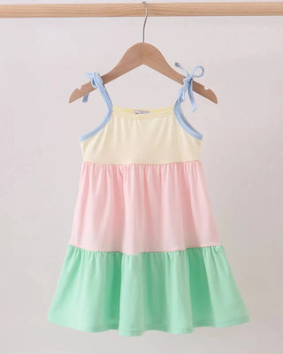 Color-blocked dress with yellow, pink, and green sections hanging on a wooden hanger against a white background.