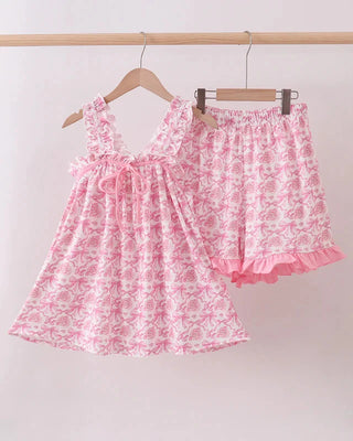 Pink floral dress and bloomers on hangers against a white background