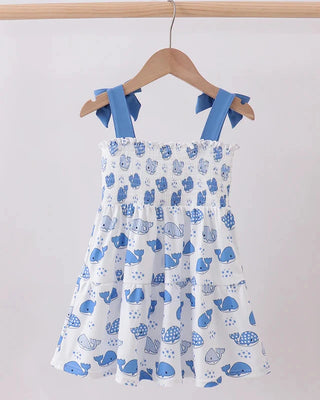 Children's dress with blue whale pattern on a hanger against a white background