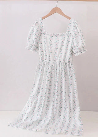 Floral dress hanging on a wooden hanger against a plain background