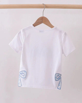 White t-shirt with blue designs on a wooden hanger against a white wall